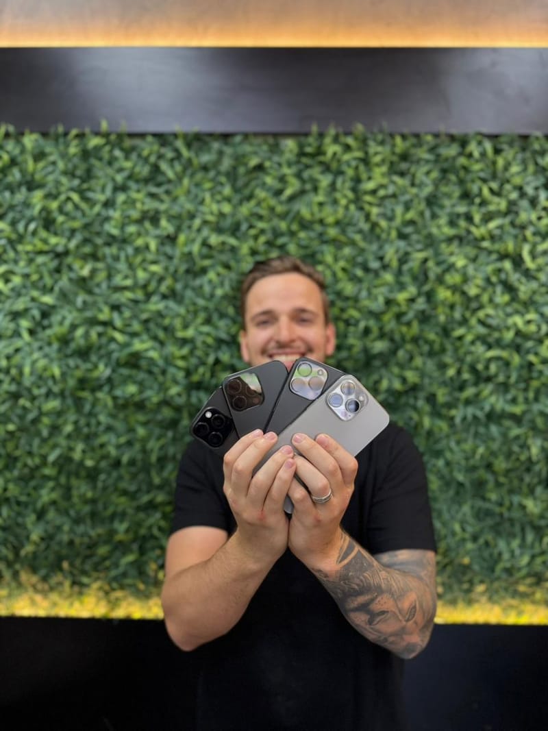 Atendente da South Import's segurando quatro iPhone Pro